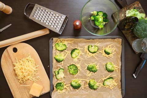 Overhead view of ingredients for smashed broccoli with cheese are on dark kitchen table