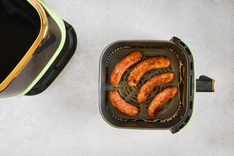 Natural casing sausages in an air fryer, being cooked at high heat. This activity shows the process