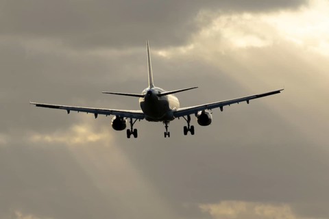 Commercial passenger airliner jet aircraft in flight on approach to land at sunset at London