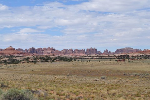 Wide desert landscape with distinctive rock structures under a slightly cloudy sky, Canyonlands