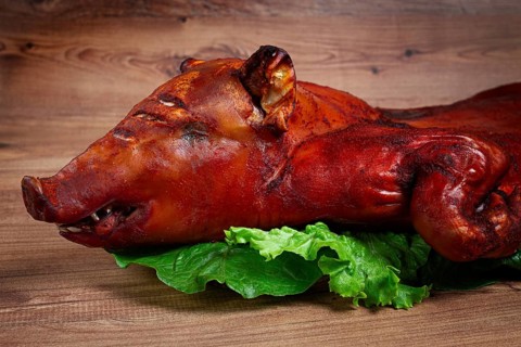 Baked, fried piglet, on a wooden table, no people, The whole piglet is baked and served on the