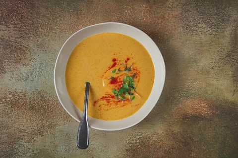 Pumpkin cream soup, in a white bowl on a textured background, top view, homemade, no people, rustic