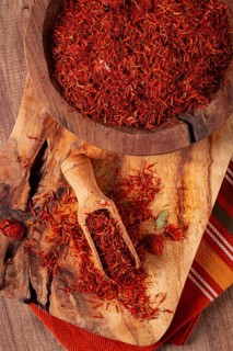 Spice saffron threads, in a wooden bowl, on a wooden table, top view, close-up