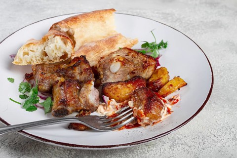 A plate with leftover pork kebab, with bread, on a white plate, close-up, there are no people