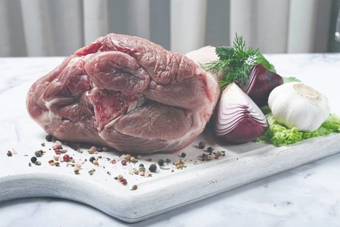 Raw pork knuckle, on a wooden chopping board, with spices, close-up, top view, no people