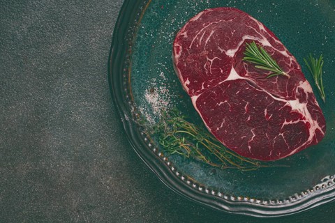 Steak made from fresh beef, with herbs and various spices, on a plate, ready to cook, there are no