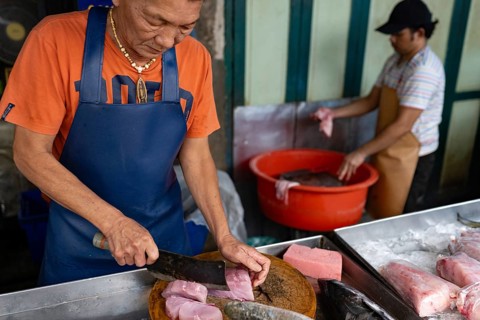 Bangkok, Thailand. March 10th 2025 A fishmonger chops tuna steaks in street market stall in