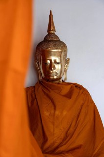 A golden Buddha image covered in orange cloth in preparation for cleaning at Wat Pho Temple complex