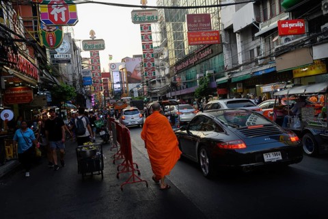 Bangkok, Thailand. February 18th 2025. A Buddhist monk walks along Yaowarat Road, busy with