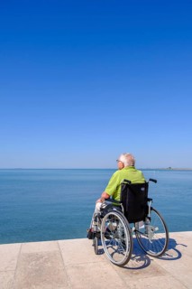 Senior in wheelchair looking at the sea, vacation with a handicap, Grado, Julian-Friuli, Adriatic
