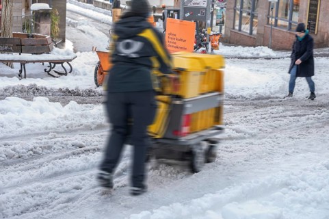 Movement, postman walking with loaded handcart on wintry roads in the city, Nuremberg, Middle