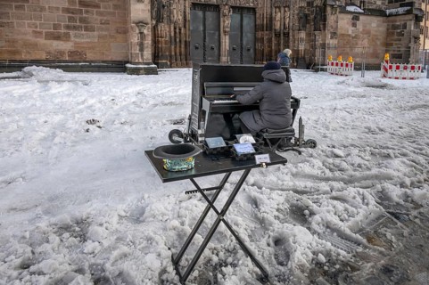Musician playing a piano in the snow in front of St. Lorenz Church, Nuremberg, Middle Franconia,
