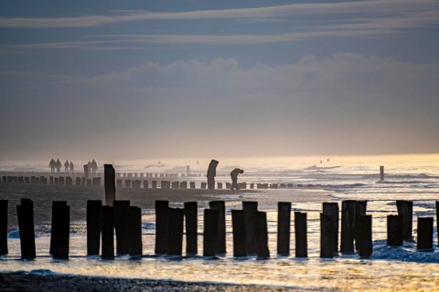 Winter on the North Sea, sunset at sea, beach walkers, coastal protection, through wooden posts,