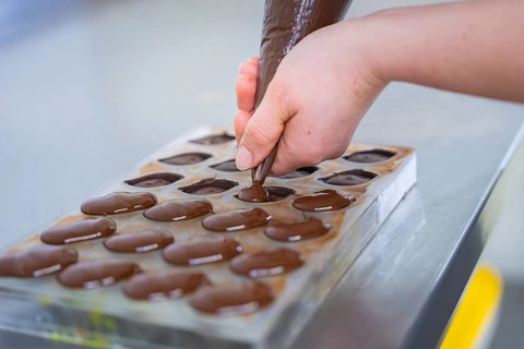 Closer look at hands filling a chocolate mold, vegan chocolates production, Haselstaller Hof,