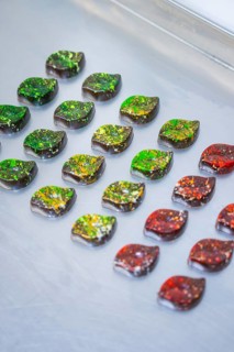 Chocolates in intense colors, decorated in leaf shapes, lie on a surface, vegan chocolates