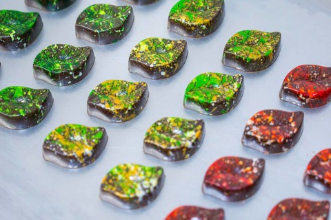 Colourful chocolates shaped like autumn leaves, arranged on a platter, vegan chocolates production,
