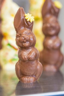 Chocolate bunny made from milk chocolate with a small yellow flower as decoration, Easter