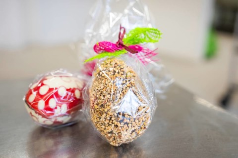 Gift wrapping of Easter eggs made from sweets and nuts in transparent foil, Easter production of