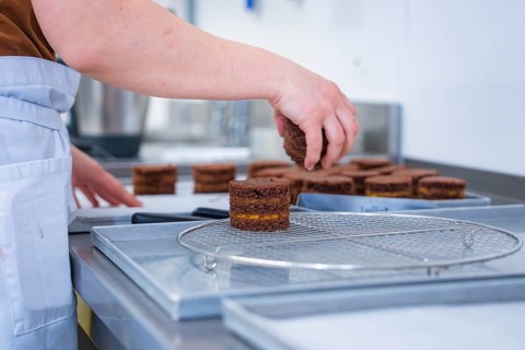 Person places cookies on a grid in the kitchen, vegan cake production, Haselstaller Hof, Gechingen,