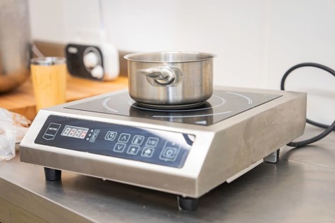 Stainless steel pot on an inductive hotplate in a modern kitchen environment, vegan cake