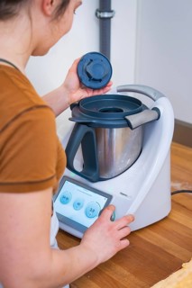 Person places the lid on a food processor during preparation, vegan cake production, Haselstaller