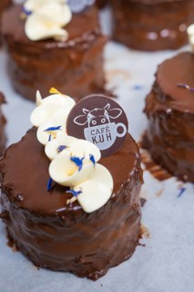 A chocolate covered cake decorated with white chocolate and logo, Vegan Tart Production,