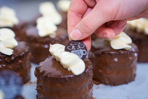 A small chocolate dessert is decorated with a café logo, Vegan Törtchen Produktion, Haselstaller