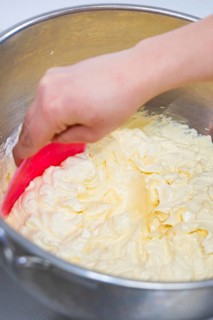 Hand stir buttercream in a metal bowl with a pink dough spatula, vegan cake production,