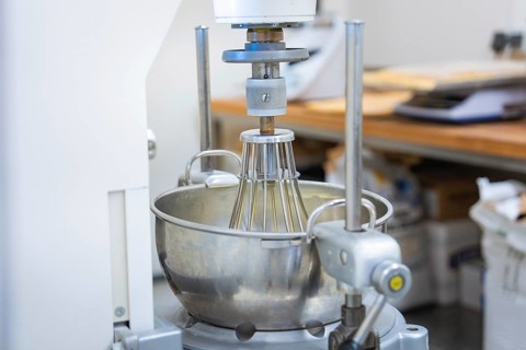 An industrial kitchen mixer with a large metal mixing container in a bakery, vegan cake production,