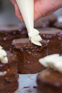 A cake is decorated with cream while several chocolate cakes are waiting, Vegan Tartchen