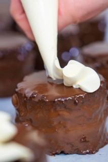 Hand decorated a chocolate cake with cream from a piping bag, vegan cake production, Haselstaller