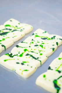 White chocolate bars with green splashes and patterns on a table, vegan chocolate production,