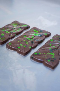 Dark chocolate bars with green dots and lines on a table, vegan chocolate production, Haselstaller