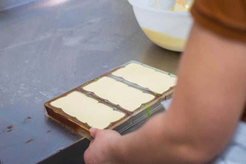 Hands holding chocolate molds in a work area on a table, Vegan Chocolate Production, Haselstaller
