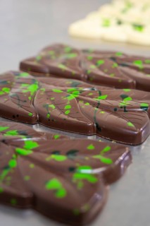 Close-up of dark chocolate bars with green patterns on a table, vegan chocolate production,