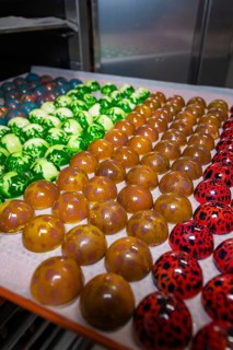 Tray with shiny chocolates in various colors and patterns, Easter production of regional products,