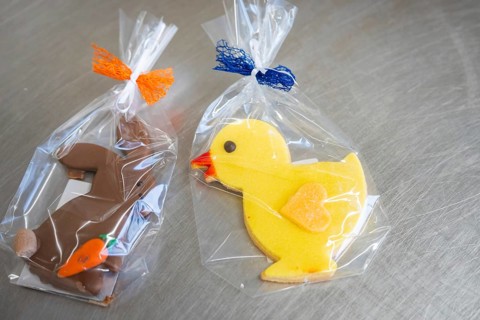 Yellow duck cookie and brown rabbit cookie, both wrapped in foil with colorful ribbons, Easter