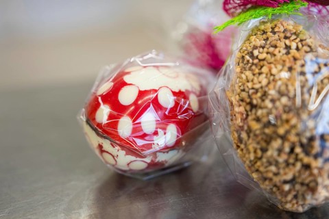 Chocolate Easter egg with nuts and a red and white egg, both packed in plastic, Easter production