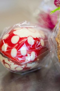 Red and white dotted Easter egg wrapped in plastic film on a metallic surface, Easter production of