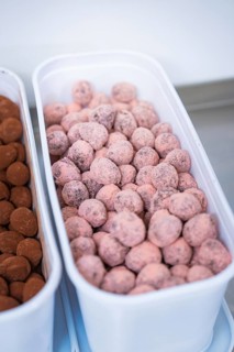 A container full of pink chocolates in a kitchen, chocolate quail eggs, Easter production,