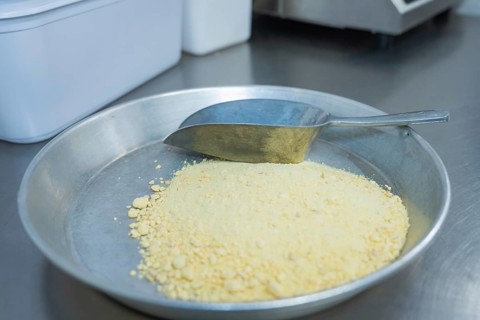 Yellow powder on a tray with a metal scoop in a kitchen setting, chocolate quail eggs, Easter