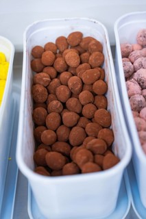 Container full of brown chocolate chocolates in a kitchen, chocolate quail eggs, Easter production,