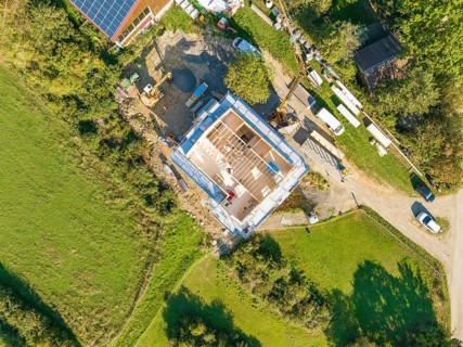 Aerial view of a construction site with grassy areas and an assembled house under construction,
