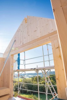 Timber building under construction with scaffolding and views of the landscape under blue sky,