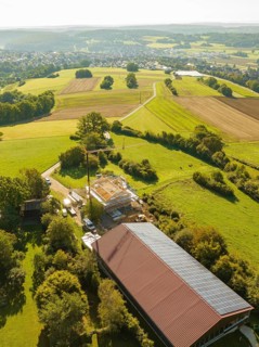 Panoramic view of landscape with fields and small construction site next to a solar building,