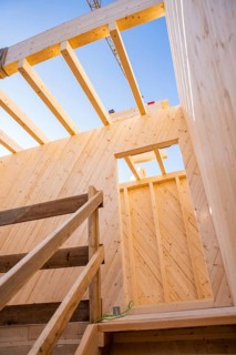 Looking up through the wooden structure of a building on blue sky, timber house construction,