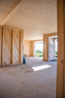 Interior view of a wooden building under construction with large amounts of light, timber house