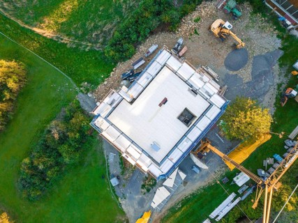 Aerial view of a construction site with building foundation and crane in a green landscape, timber