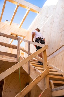 Workers climbing a wooden staircase in a partially converted building, timber house construction,