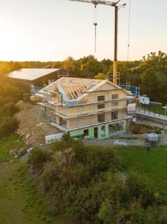 Building under construction, surrounded by scaffolding, at sunset in a rural area, timber house